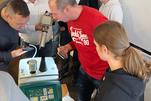 Training at a Robatech melter: People standing around the device and looking into it with interest