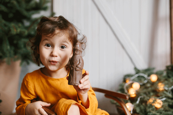 Little girl holding up a chocolate Santa Claus to the camera